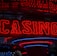 Neon lights display the word 'CASINO' in bright red, standing out against a dark background. The vibrant glow reflects a lively and bustling atmosphere.